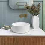Phoenix Vivid Slimline wall basin mixer in brushed gold, shown above a white vessel basin in a modern bathroom vanity setting