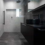 Phoenix Vivid Slimline vessel mixer in matte black beside a black above-counter basin in a modern bathroom vanity setting