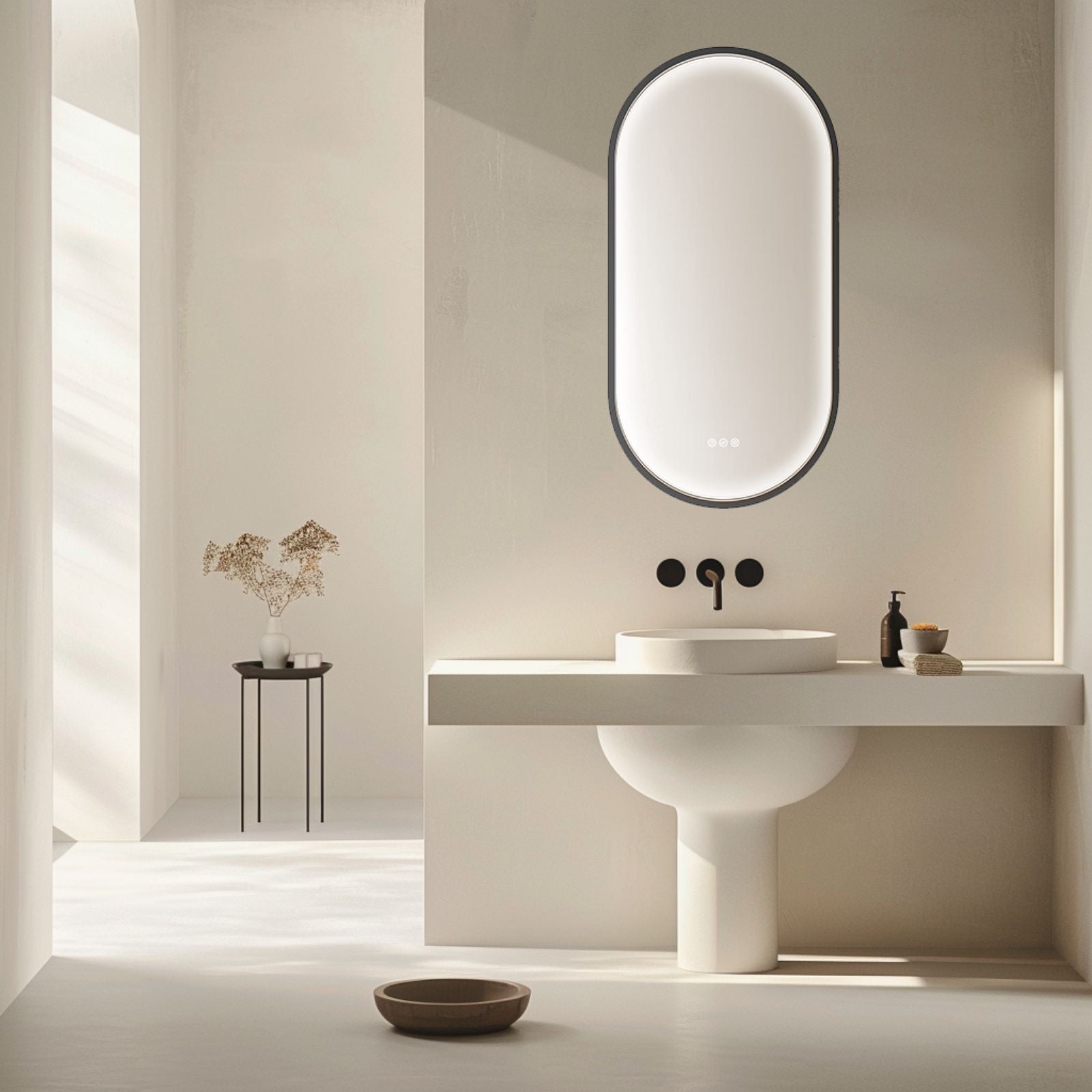 Radiant Kapsel oval LED mirror in black, shown above a bathroom vanity with glowing edge light in a modern ensuite