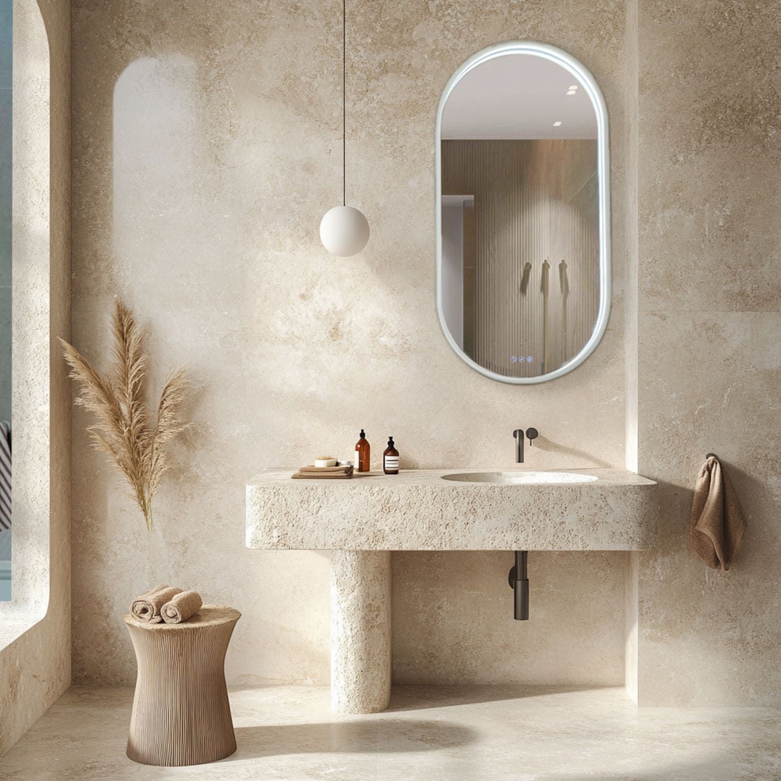 Radiant Kapsel oval LED mirror in white, shown in a bathroom above a stone vanity with sink and black tapware