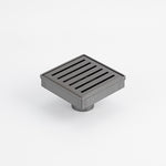 Radiant square slotted floor grate in gun metal grey, stainless steel, shown on white background with outlet underneath