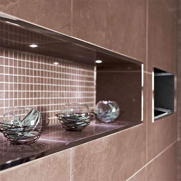 Radiant black tiled shower niche in a wall, with a long horizontal recess and smaller square niche beside it