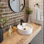 Round white above-counter basin with black mixer tap on a timber vanity in a bathroom setting