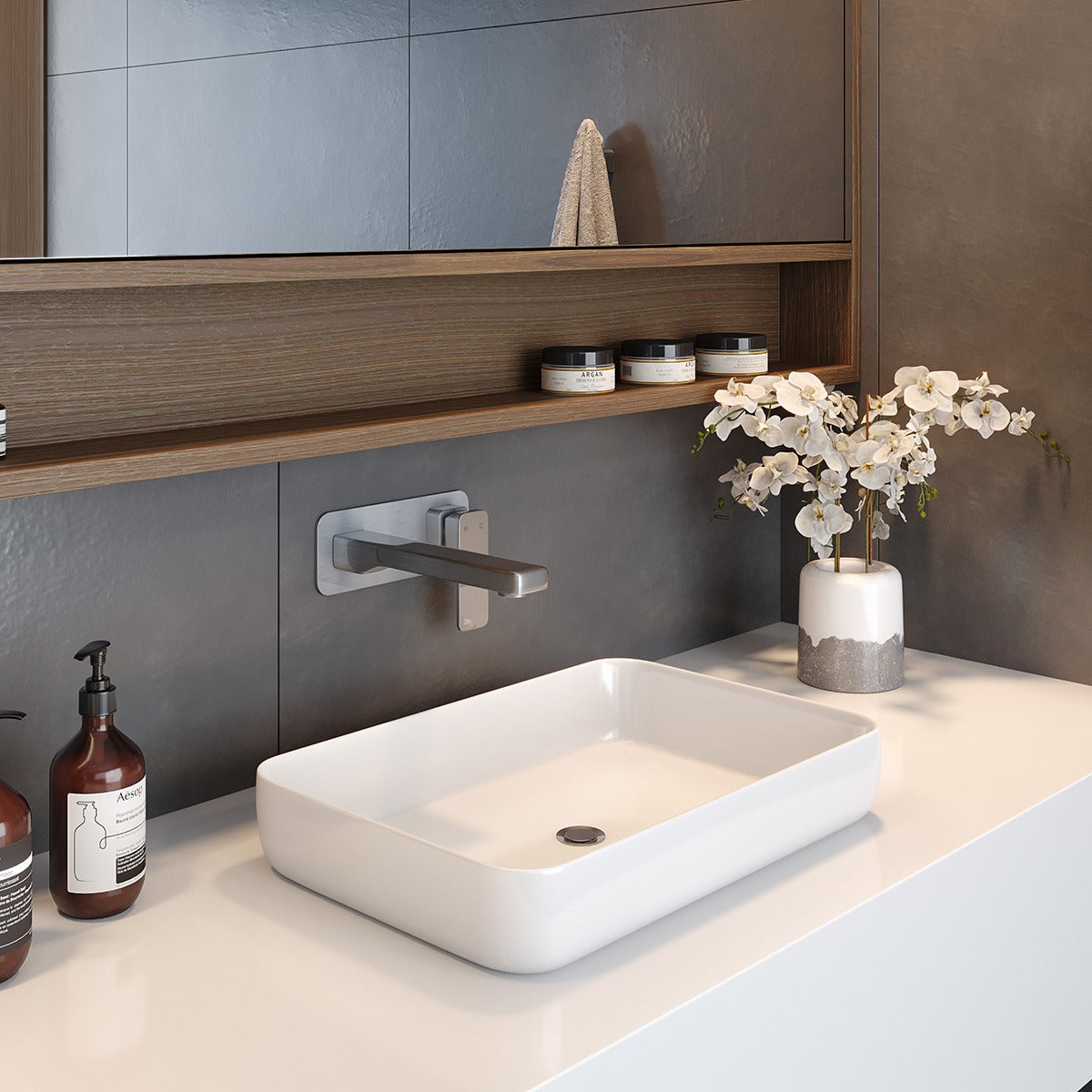 Brushed nickel Raymor Edge II robe hook mounted on a dark wall beside a basin and shelf in a modern bathroom