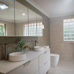 Large mirrored shaving cabinet above white vanity in modern bathroom, with double basins and light grey tiled walls