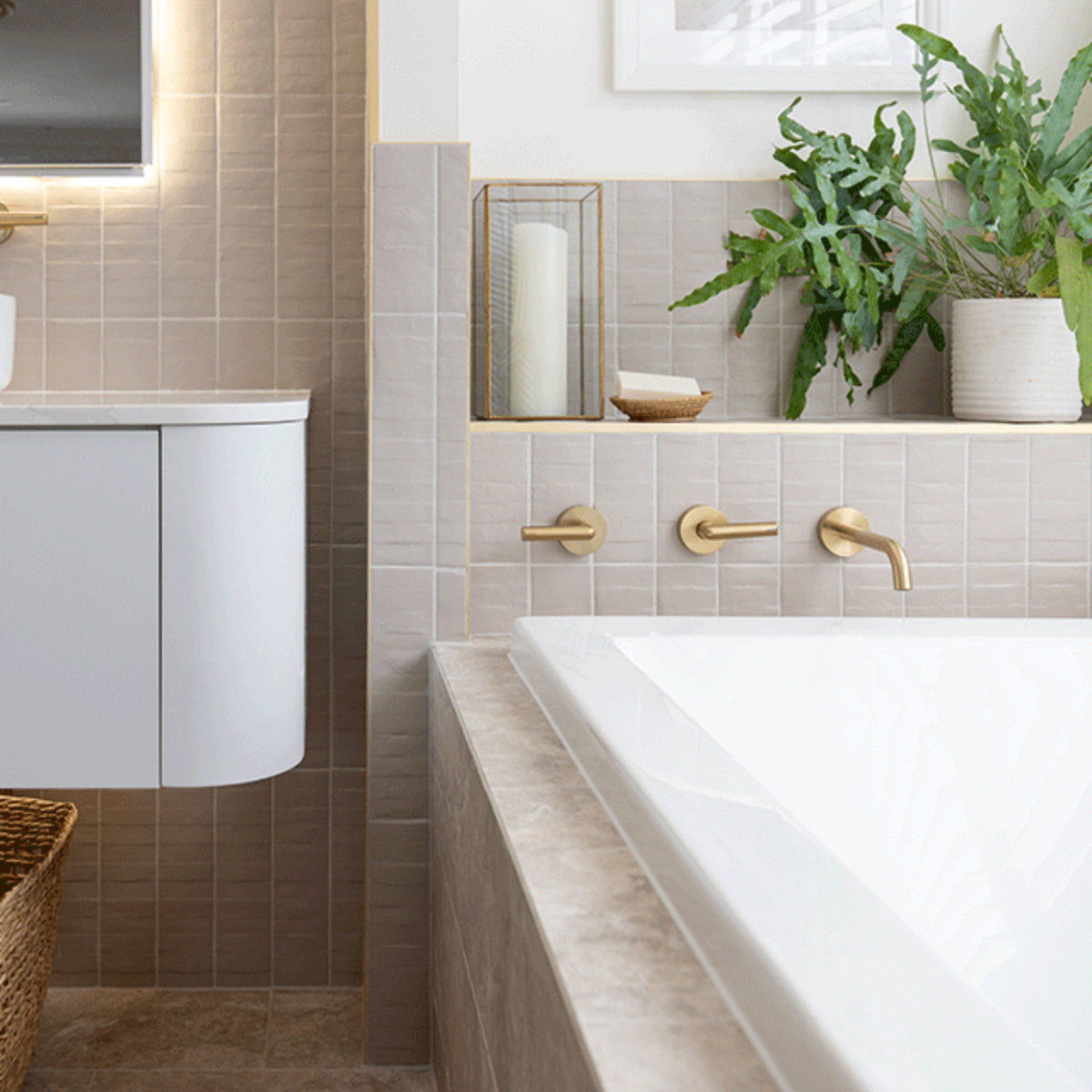 Caroma Newbury white island bath inset in tiled hob, with reclined end and gold wall taps in a modern bathroom
