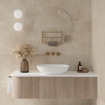 Thermogroup Ablaze round magnifying mirror clip-on beside a bathroom vanity, shown in a beige tiled wall setting