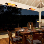 Black Thermogroup wall-mounted outdoor heater glowing above an alfresco dining area with two infrared heaters installed on the beam