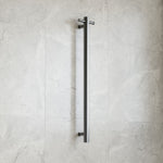 Thermogroup gunmetal round vertical heated towel rail, single bar, wall mounted on light stone bathroom tiles