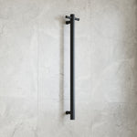 Thermogroup matte black round vertical single-bar heated towel rail mounted on a light tiled bathroom wall