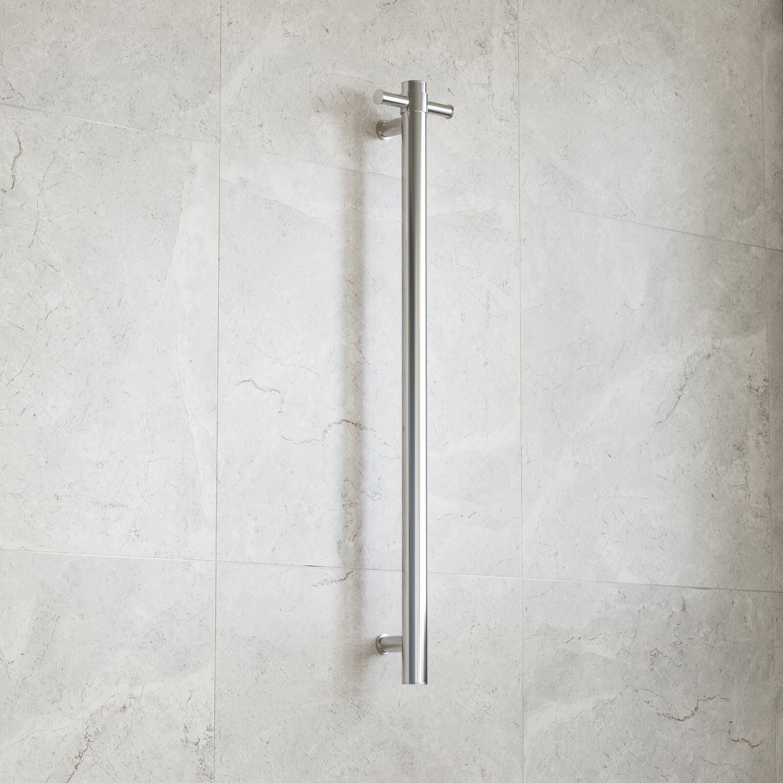 Thermogroup polished stainless steel heated towel rail, straight vertical single bar, wall mounted against light stone tiles