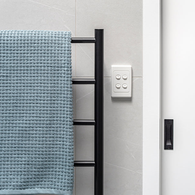 Thermogroup Thermorail black round towel ladder with 5 bars mounted beside a tiled shower wall with towel and control panel