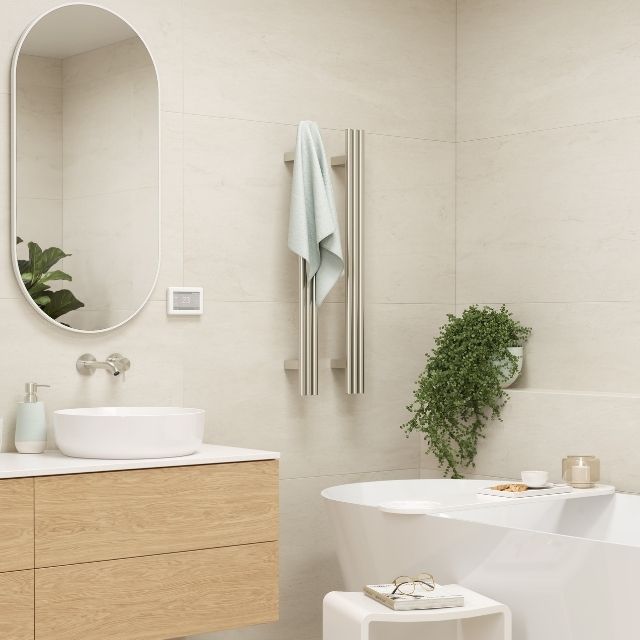 Thermogroup polished stainless vertical heated towel rail in a modern bathroom, with towel and round triple tube bars