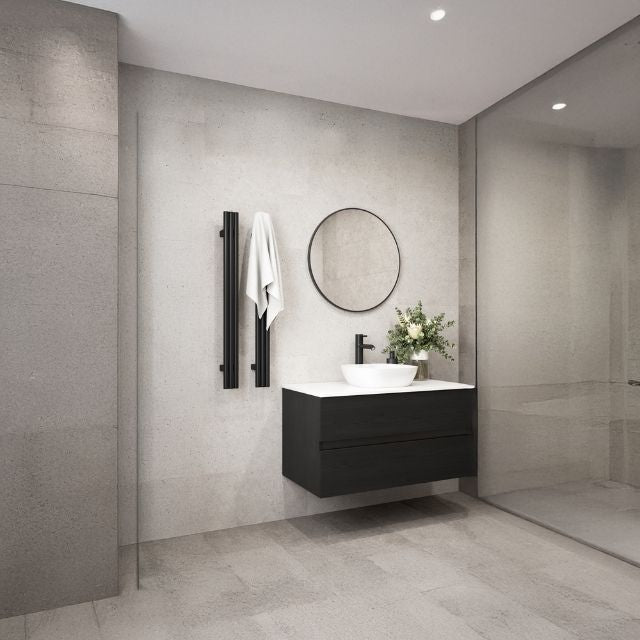 Matt black Thermogroup vertical heated towel rail on a grey bathroom wall beside a vanity and round mirror