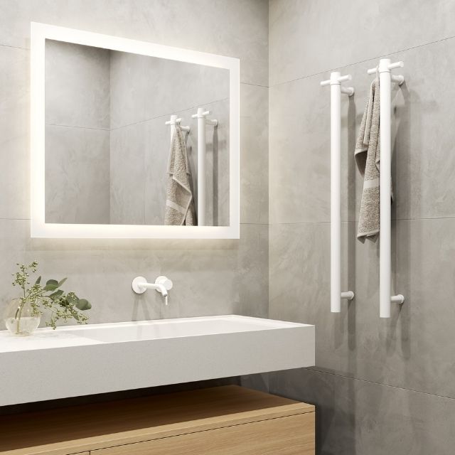 Matt white Thermogroup vertical heated towel rail mounted beside a bathroom vanity with towel hanging on it