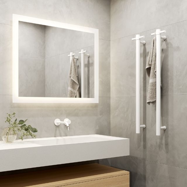 Thermogroup Matt White vertical heated towel rail in a modern bathroom beside a vanity and illuminated mirror