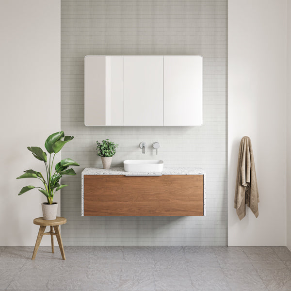 Timberline Ainsworth wall hung vanity with woodgrain front, speckled waterfall top and white above-counter basin in bathroom setting