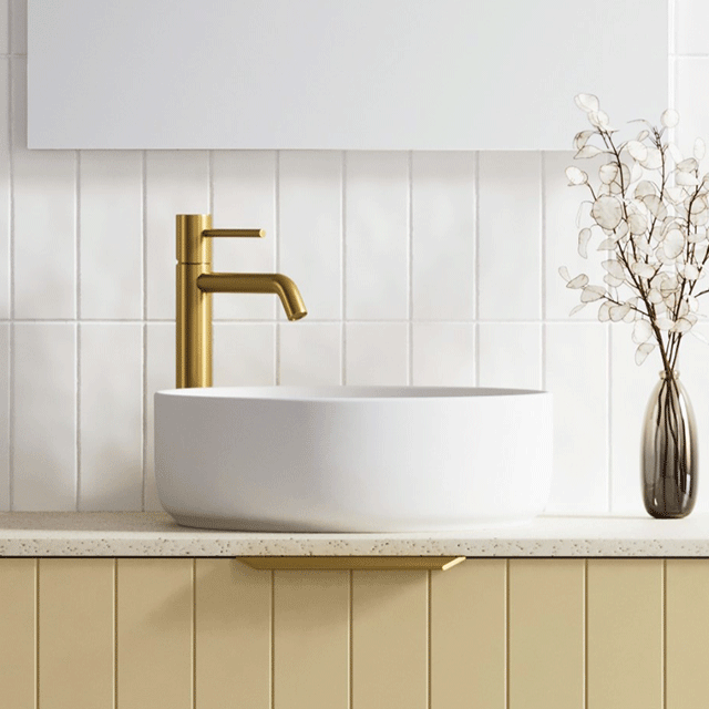 Timberline Allure white round above counter basin in gloss finish, styled on a vanity with gold tapware and white tile splashback