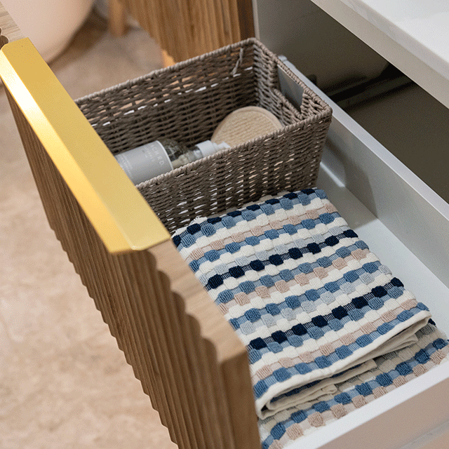 Timberline Santos Apollo fluted vanity drawer with woven basket and folded towels, side view of timber finish and gold handle