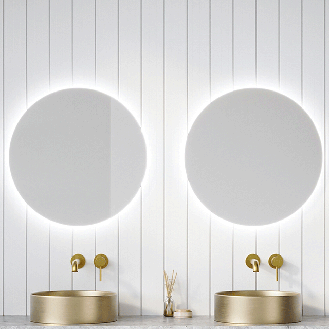 Timberline Oxford round mirror with optional LED backlighting, shown in a bathroom with two mirrors and gold basins