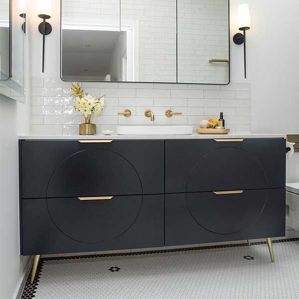 Timberline Sutherland House Retro floorstanding vanity in black, with white top, brass handles and tapered legs in bathroom scene