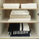 Open Timberline Sutherland House storage cabinet with oak shelves holding folded towels, interior view