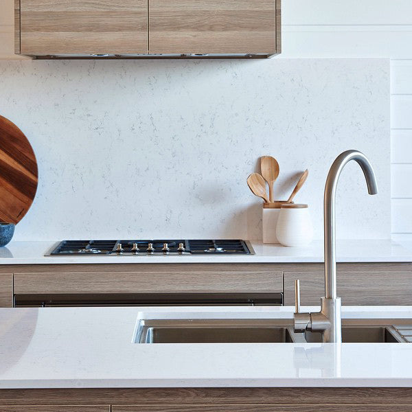 Caroma Titan stainless steel gooseneck sink mixer in a modern kitchen, shown above a white sink and benchtop.