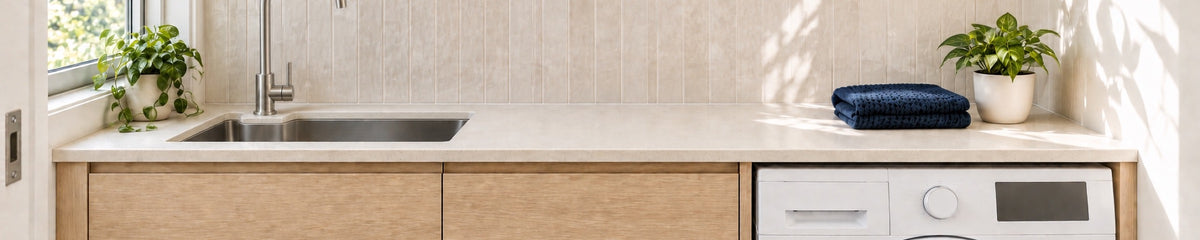 Compact stylish laundry with oak cabinetry, ivory tiles, a tall brushed nickel tap and a washing machine.