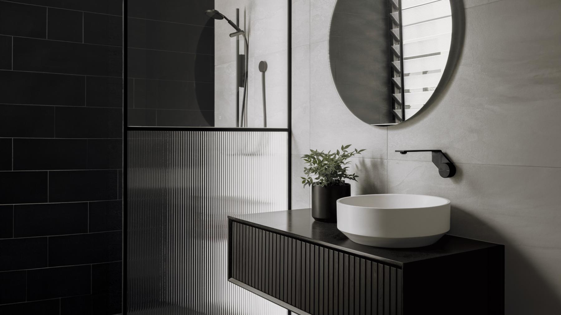 Black fluted vanity with matte black tapware, round mirror and Phoenix NX IKO rail shower