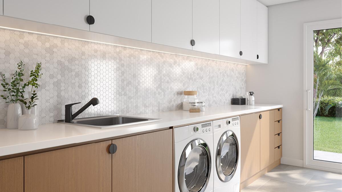 Laundry with deep tub, black mixer, white cabinets and timber benchtop