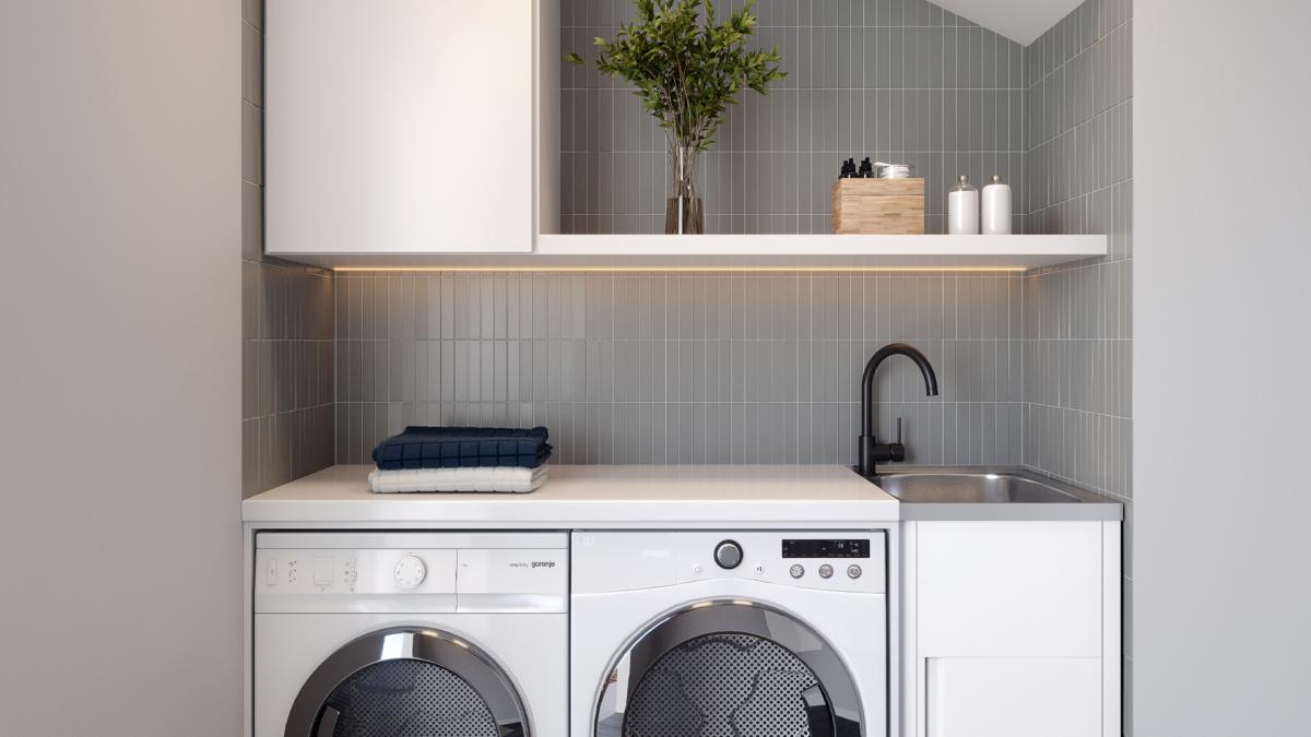 Grey tiled laundry with white benchtop, black mixer and stainless tub