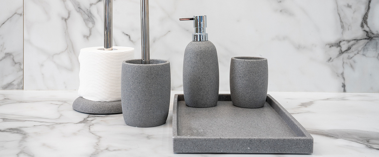 Grey and white textured bathroom accessories against a marble  backdrop