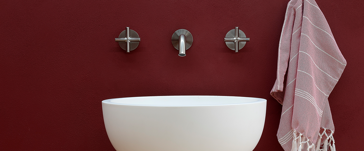 Red bathroom with round white sink and chrome tapware